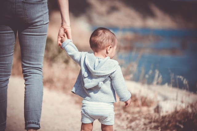 woman holding hands and walking with baby outside