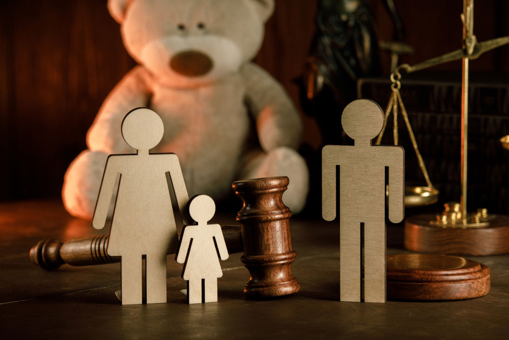 Wooden figures of family with teddy bear and gavel on a table close-up